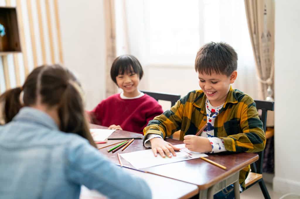 机を囲んで笑顔で学ぶ子どもたち