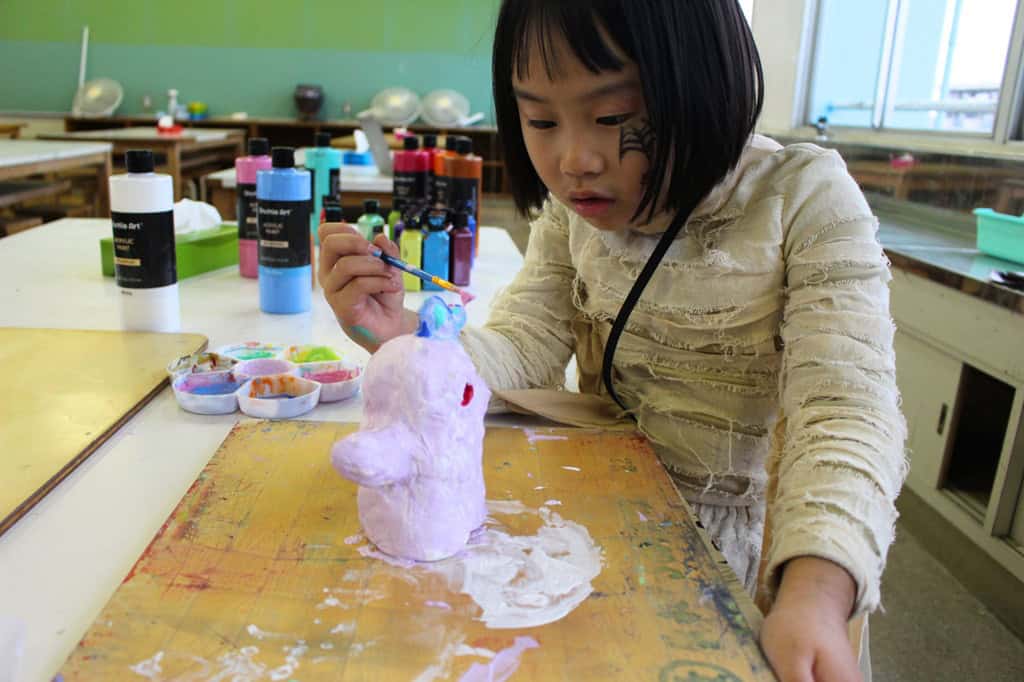 アフタースクール陶芸クラスのACESガール、自分の陶器に絵を描く