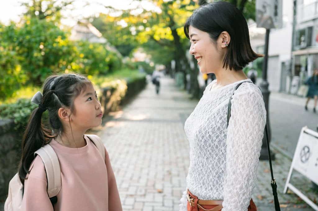 学校帰りに笑顔で話す母親と娘