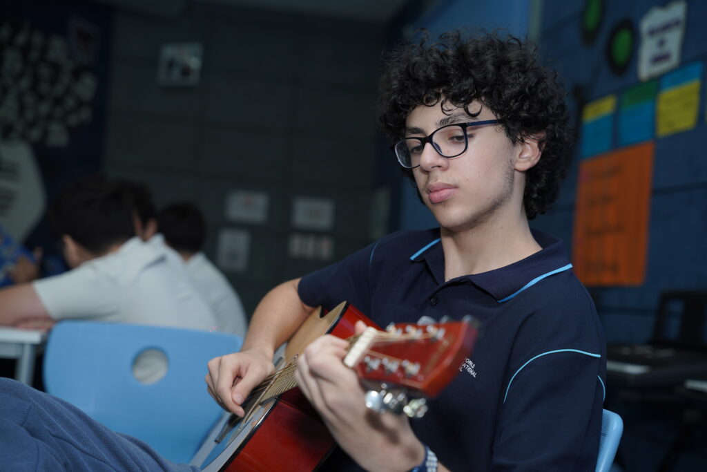 Student playing on his guitar