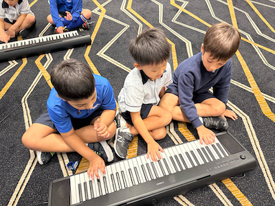 Primary School students learning to play the keyboard in music lesson Well-rounded education at One World International School in Singapore