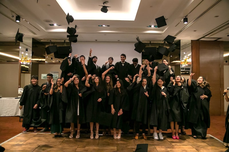 Group of graduating students at OWIS doing the hat toss at their graduation ceremony